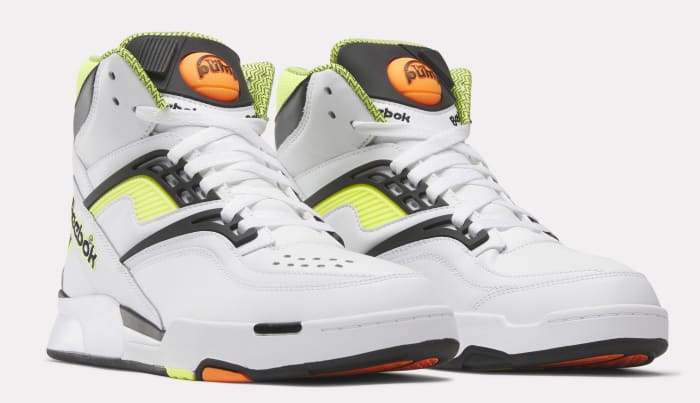 Side view of white, black, and yellow Reebok shoes.